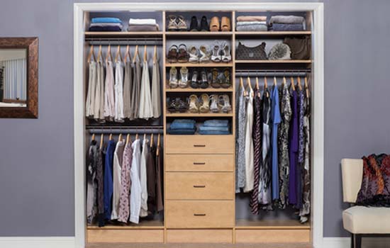 Reach-in closet with warm maple shelving, hanging rods and drawer units