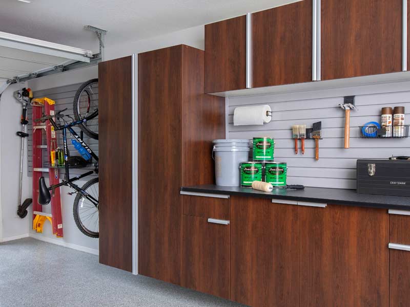 Custom garage cabinets in dark walnut with workbench and slatwall organization